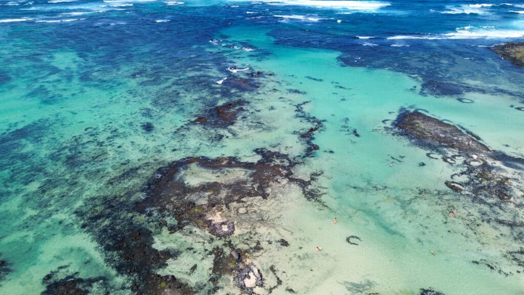 Lagon turquoise et sable blanc de Caletón Blanco entouré de roches volcaniques noires